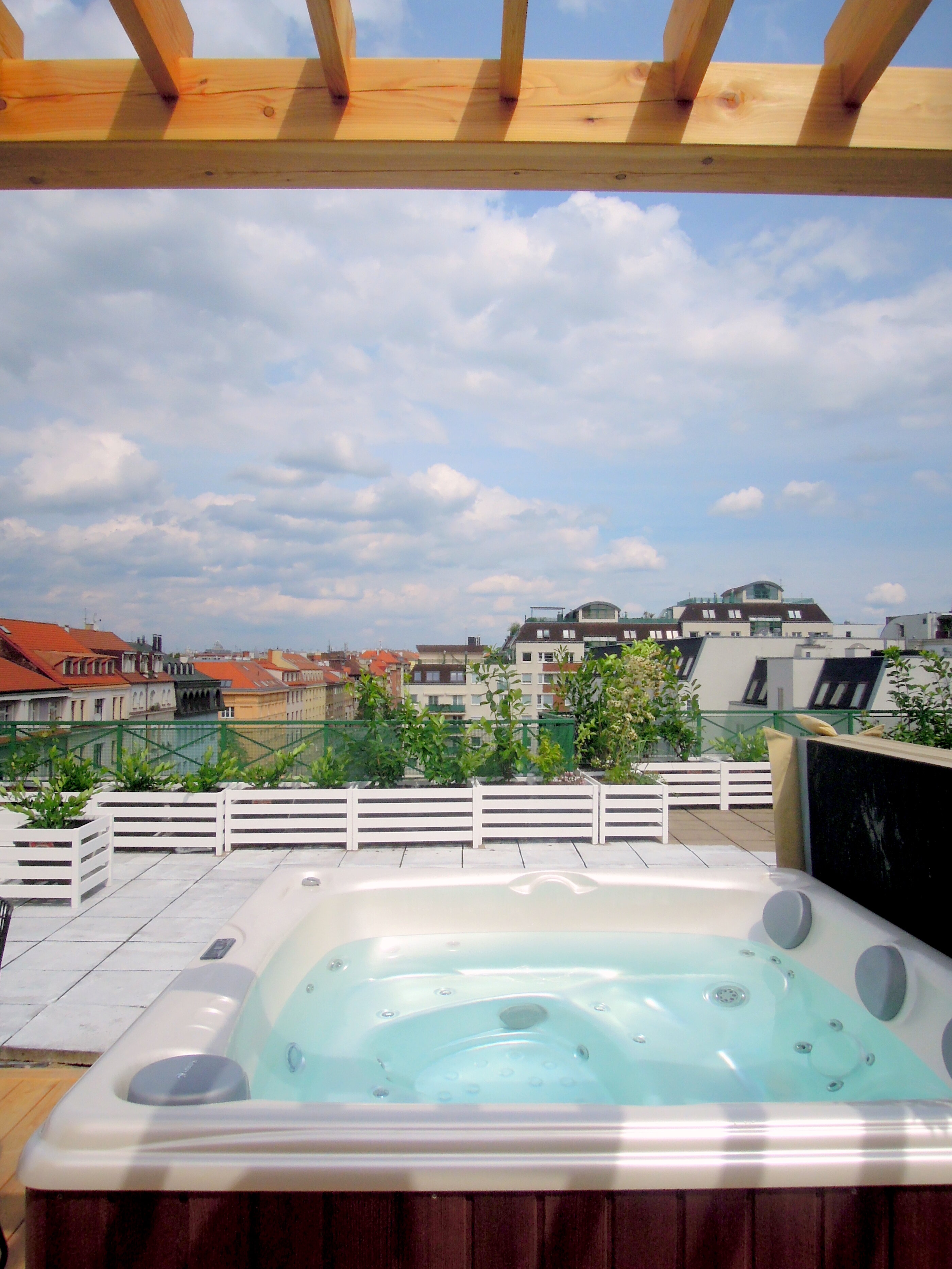 Aston hot tub by USSPA on an outdoor terrace with a pergola in a modern elegant setting.