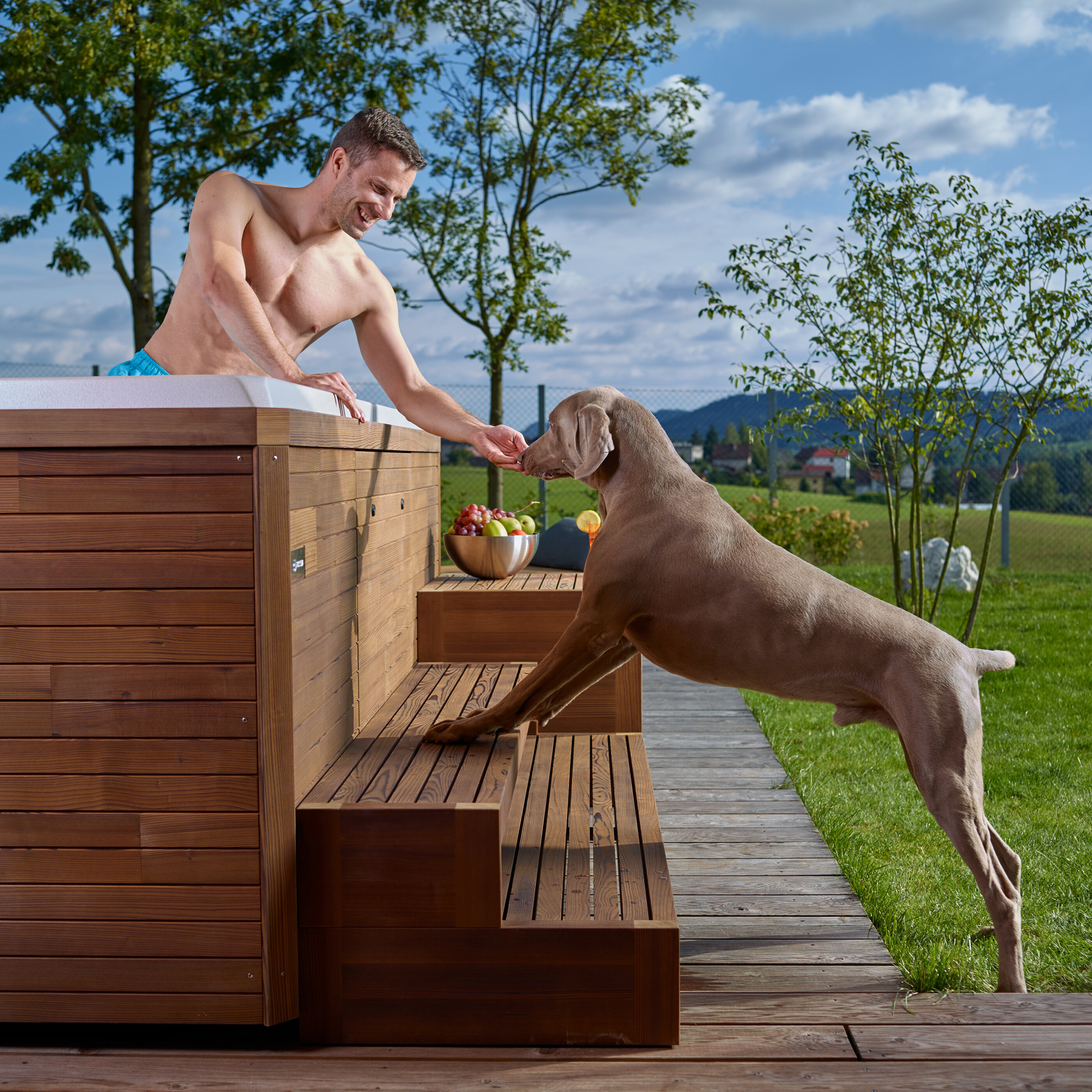 USSPA premium whirlpool in the garden with wooden steps – man in spa and dog beside relaxing.