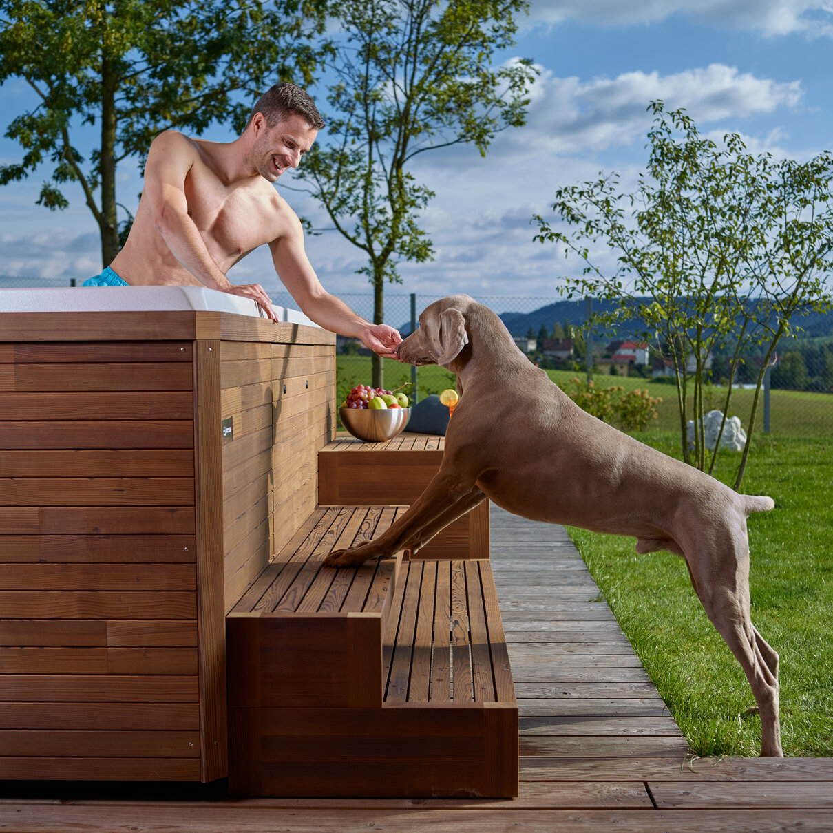 USSPA premium whirlpool in the garden with wooden steps – man in spa and dog beside relaxing.